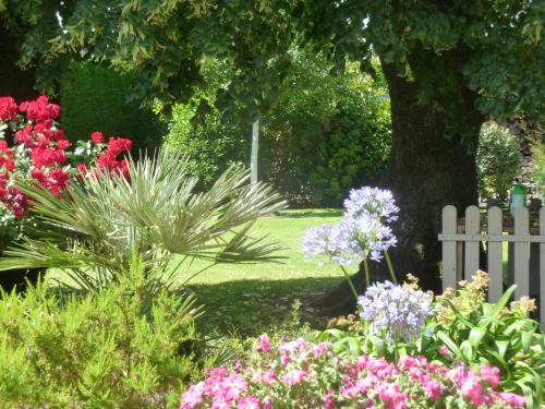 a white picket fence in a garden with flowers at Les Bruyères du Mont in Céaux