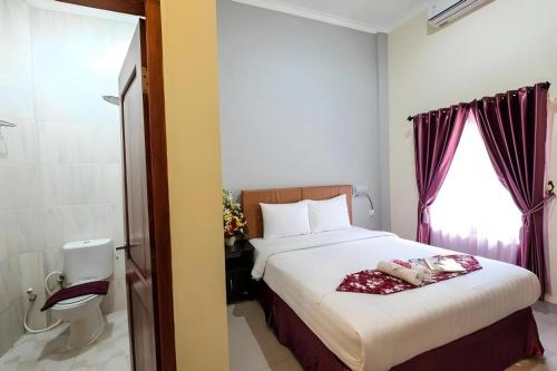 a bedroom with a large bed and a window at Malioboro Garden Hotel Yogyakarta in Yogyakarta