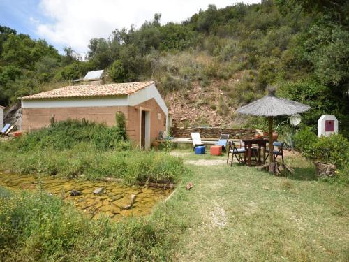 a house with a table and an umbrella in a yard at Cottage São Luís near Vicentine Coast Park in Troviscais