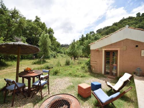 a patio with a table and chairs and an umbrella at Cottage São Luís near Vicentine Coast Park in Troviscais