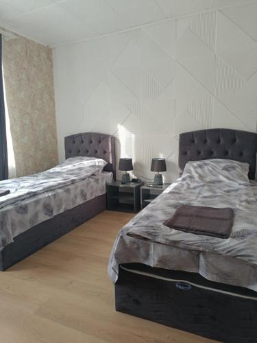 ein Schlafzimmer mit zwei Betten und zwei Tischen mit Lampen in der Unterkunft Апартамент за гости Парадайс in Malko Tŭrnovo