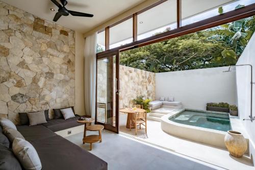 a living room with a large window and a soaking tub at Casa Beso Balangan in Badung