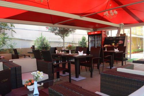 um restaurante com mesas e cadeiras e um guarda-sol vermelho em Mini hotel Delphin em Adler