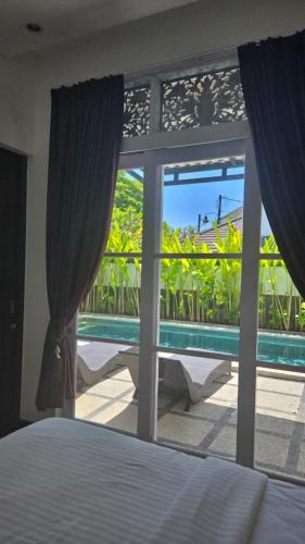een slaapkamer met uitzicht op een zwembad door een raam bij Villa Don Bose 8 in Jimbaran