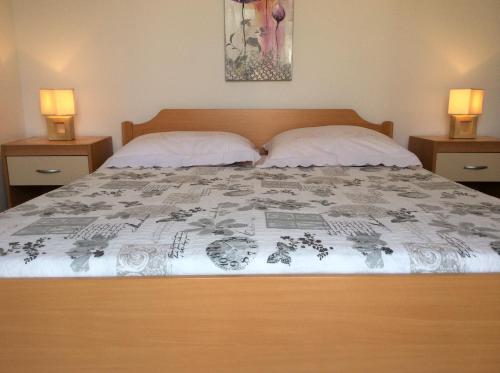 a bedroom with a bed with two pillows and two lamps at Apartmani Agard in Brodarica