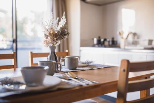 a wooden table with two cups and a vase with flowers at R Residences 難波南 I in Osaka