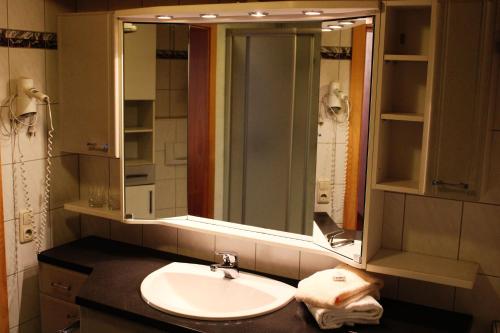Bayerische Gastwirtschaft Dimpfl-Stadl في لام: حمام مع حوض ومرآة كبيرة