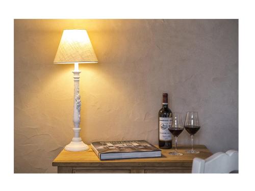 a table with a lamp and two glasses of wine at La Sauternaise, luxury Boutique B&B in Sauternes