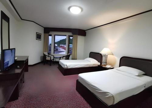 Royal Diamond Hotel في فيتشابوري: غرفة فندق بها سريران وتلفزيون بشاشة مسطحة