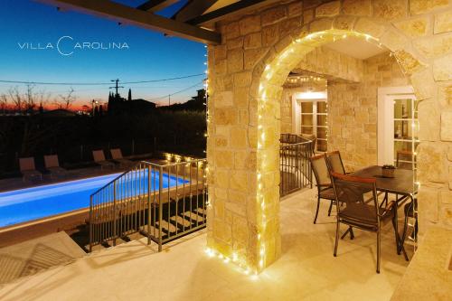 un patio avec une table et des chaises à côté d'une piscine dans l'établissement Villa Carolina, à Izola