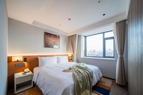 a bedroom with a large white bed with a window at Citadines Luyang Hefei in Hefei