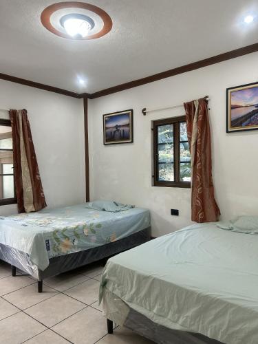 Hospedaje Nicolas في سان خوان لاجونا: سريرين في غرفة ذات نافذتين