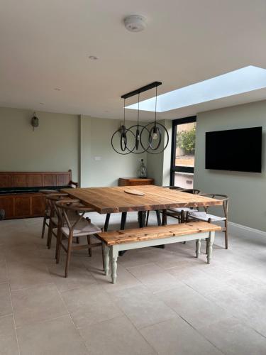 Lynwood House, Bratton في Bratton: غرفة طعام مع طاولة خشبية كبيرة وتلفزيون بشاشة مسطحة