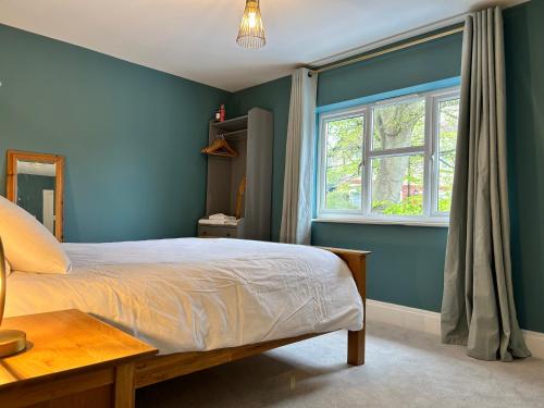 a bedroom with blue walls and a bed and a window at Lynwood, 5 bed, 4 bath, private large drive in Bratton