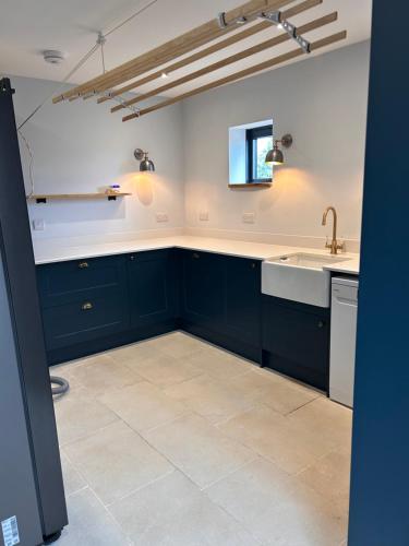 Lynwood House, Bratton في Bratton: مطبخ مع الدواليب الزرقاء البحريه والمغسله