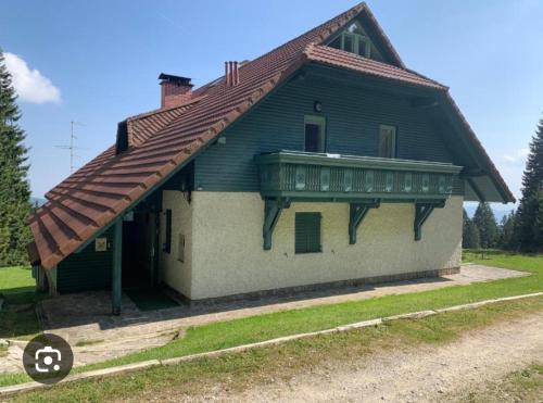 a house with a gambrel roof and a porch at Apartma Ajdovka Rogla in Rakovec