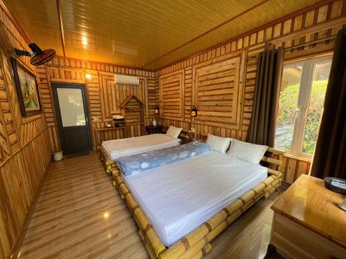 Trang An Maison Retreat في Nguyên Ngoại: غرفة نوم بها سريرين في غرفة ذات جدران خشبية