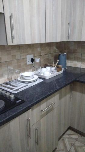 a kitchen counter with plates and dishes on it at Royal Gidlas Guesthouse in Saulspoort