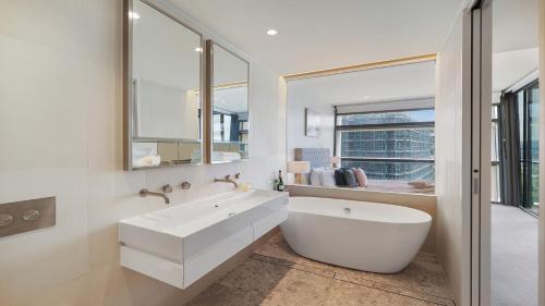 een witte badkamer met een bad en een groot raam bij Marina Belle in Shellharbour