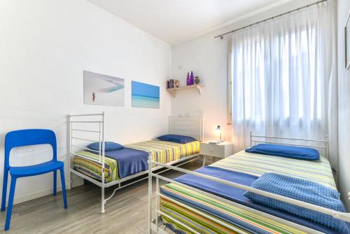een slaapkamer met 2 bedden en een blauwe stoel bij Appartamento Lucia in Capoliveri