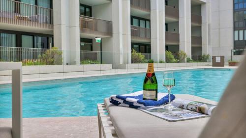 a bottle of wine and a glass next to a swimming pool at Marina Belle in Shellharbour