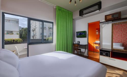 a bedroom with a white bed and a green curtain at Scarlet Hotel in Tel Aviv