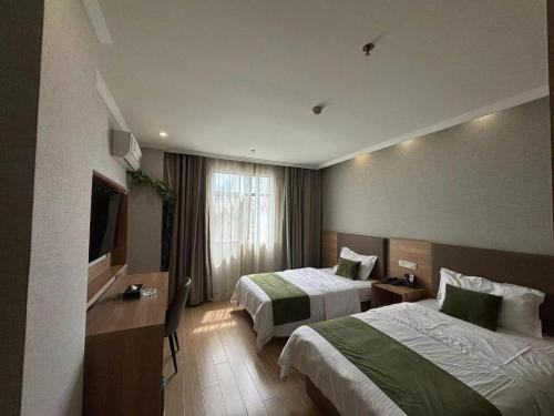 GreenTree Inn Jiangsu Suzhou Kunshan Beimen Road Express Hotel في كونشان: غرفة فندقية بسريرين وتلفزيون