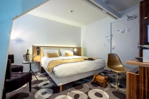 a hotel room with a bed and a chair at The Originals Boutique, Hôtel Bulles by Forgeron, Lille Sud (Qualys-Hotel) in Seclin