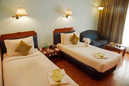 a hotel room with two beds and a couch at The Chancery Hotel in Bengaluru