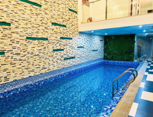 a swimming pool in a building with a brick wall at ELC Luxury Hotel Danang - An Thuong Walking Street in Da Nang