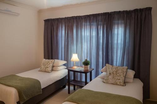 a hotel room with two beds and a window at Agapantha Cottage in Lobamba