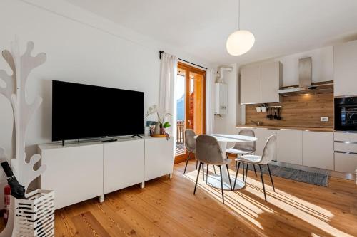 Siera View Apartment - Comfort e Relax a Sappada في سابادا: مطبخ وغرفة طعام مع تلفزيون بشاشة مسطحة