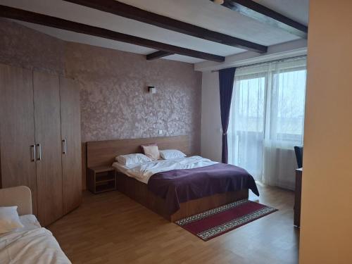 a bedroom with a bed and a large window at Pensiunea Bergtal in Râşnov