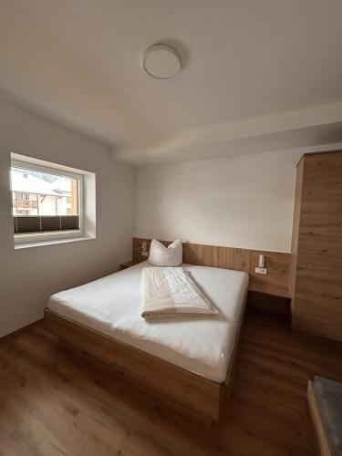 a bedroom with a bed with white sheets and a window at Höller's Bergleben in Kleinarl