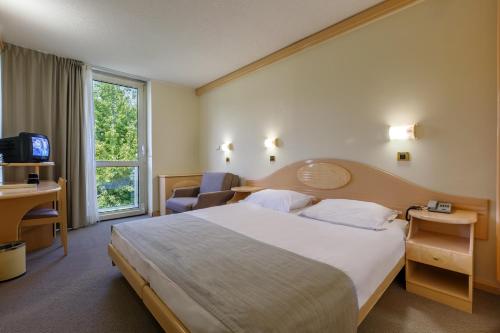 a hotel room with a large bed and a window at Hotel Istra Plava Laguna in Poreč