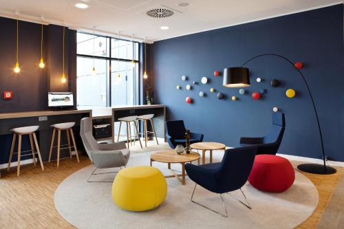 a room with chairs and tables and a blue wall at Holiday Inn Express - Kaiserslautern by IHG in Kaiserslautern