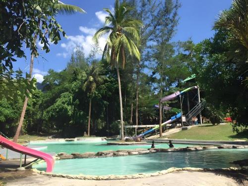 a swimming pool with slides and palm trees in a park at Ranong Resort & Laguna in Ban Samnak