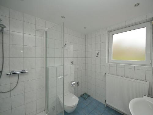 a bathroom with a shower and a toilet and a window at Haus Nixe Stranddüne in Juist