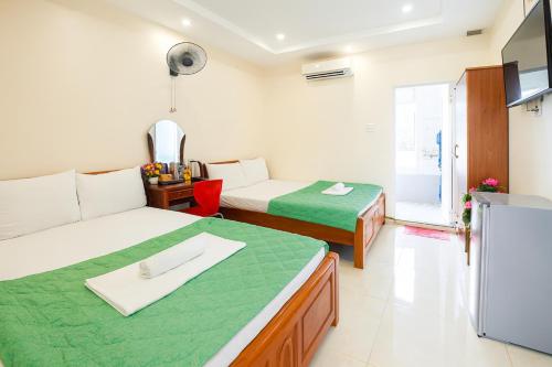 um quarto de hotel com duas camas e uma televisão em Kinh Bac Hotel Quy Nhon em Quy Nhon