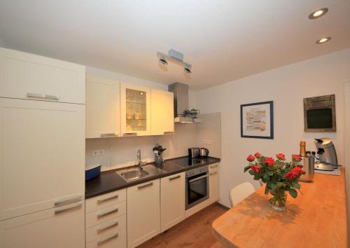 a kitchen with a table with a vase of flowers at ENA Ferien Strandhütte in Juist