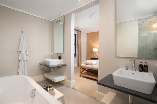 a bathroom with a tub and a sink and a mirror at The gallery luxury one bedroom apartment unit 101 in Knysna