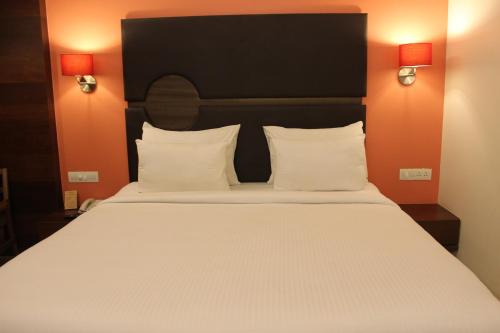 a large bed with white pillows and a black headboard at Hotel Cosmopolitan in Ahmedabad