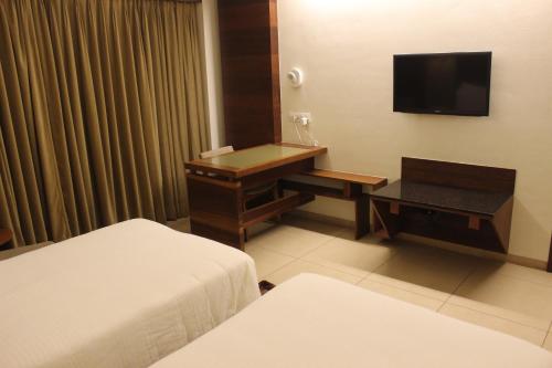 a hotel room with a desk and a television at Hotel Cosmopolitan in Ahmedabad