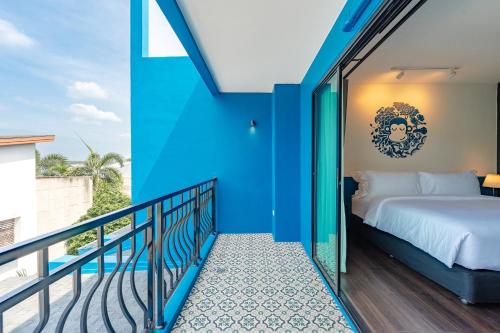 ナイハーンビーチにあるBlu Monkey Boutique Naiharn Beachの青い壁とバルコニーにベッドがある寝室