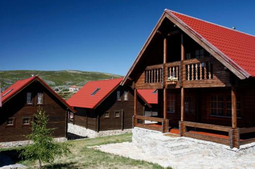 two wooden buildings with red roofs at Luna Chalets da Montanha - Serra da Estrela in Covilhã