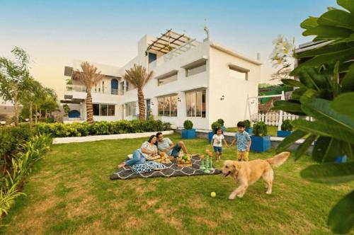 a family sitting in the yard with a dog at EKOSTAY Luxe - Hercules Villa in Igatpuri