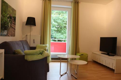 Una sala de estar con un sofá y un televisor. en Travel Apartments, en Münster