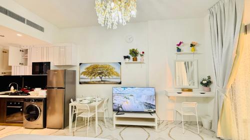 a kitchen with a refrigerator and a table with chairs at Petalz Luxury furnished studio with Balcony Swimming Pool Gym Kids play ground in Dubai