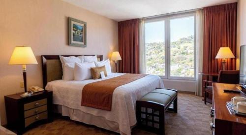 una camera d'albergo con un letto e una grande finestra di Hotel Honduras Maya a Tegucigalpa