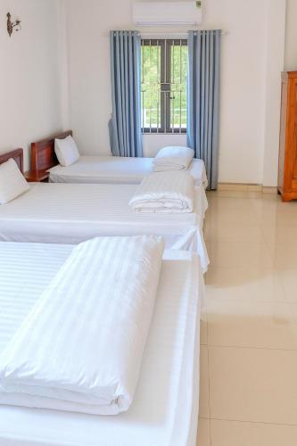 a room with three beds and a window at Thành Luân Hotel in Bak Kan
